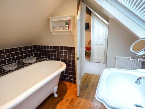 a bathroom with a bath tub and a sink at Honeypot Cottage in Kendal