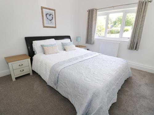 赫克瑟姆Buttercup Cottage的一间卧室，有一张白色的床和一扇窗户