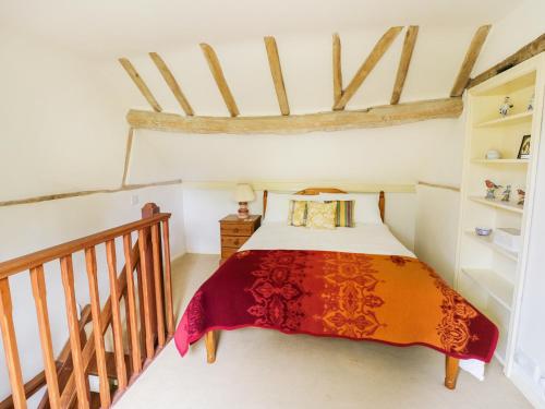 ein Schlafzimmer mit einem Bett mit einer roten Decke in der Unterkunft The Cottage in Pershore