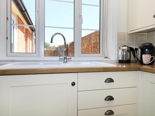 eine Küche mit einem Waschbecken und einem Fenster in der Unterkunft New Park Farm Cottage in Brockenhurst