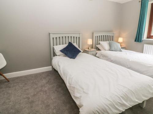 two beds in a room with white sheets and a blue pillow at 3 Trem Afon in Colwyn Bay