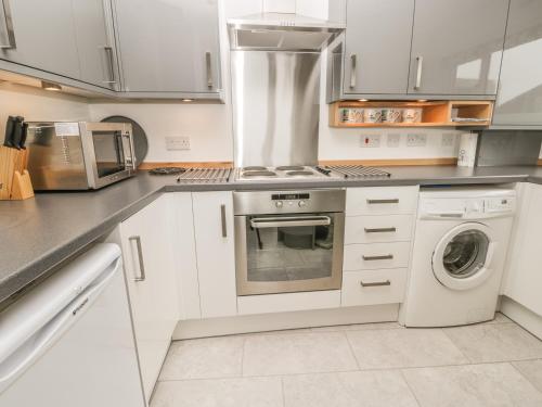a kitchen with white cabinets and a washer and dryer at Sunrise in Filey