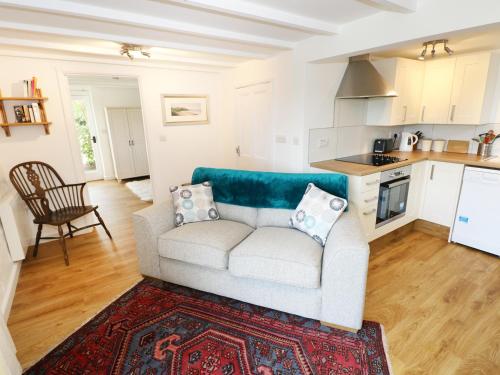 a living room with a couch and a kitchen at The Granary Cottage in Llangranog
