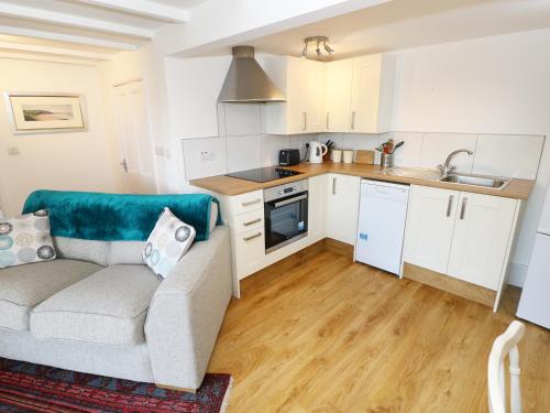 a living room with a couch and a kitchen at The Granary Cottage in Llangranog