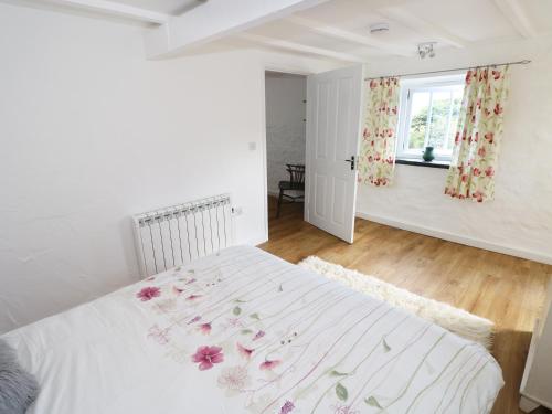 a bedroom with a white bed with flowers on it at The Granary Cottage in Llangranog