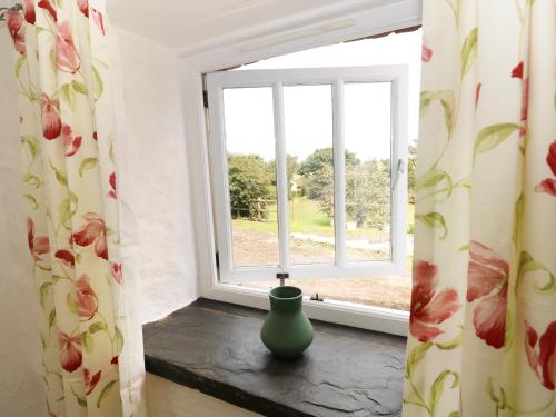 a green vase sitting on a table in front of a window at The Granary Cottage in Llangranog