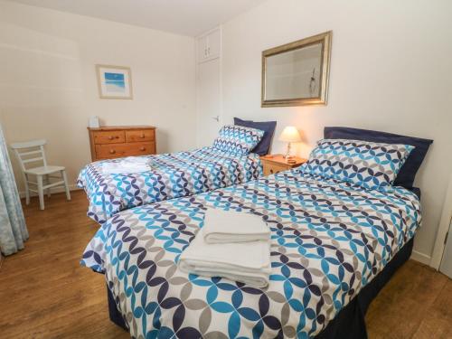 a bedroom with two beds with blue and white sheets at Trem Y Garn in Pwllheli