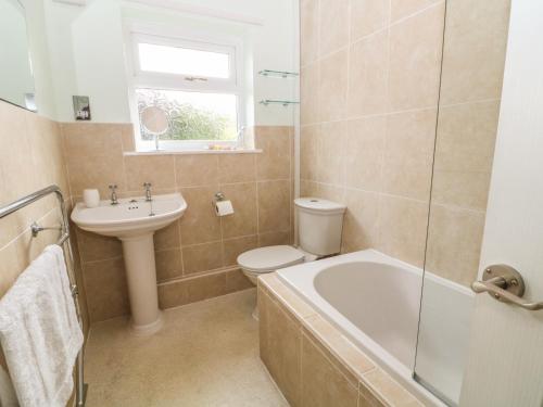 a bathroom with a sink and a toilet and a bath tub at Trem Y Garn in Pwllheli