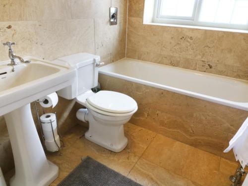 a bathroom with a toilet and a tub and a sink at Evergreen in Ilkley