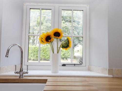 a vase of sunflowers sitting in a kitchen window at Corner View in Great Driffield