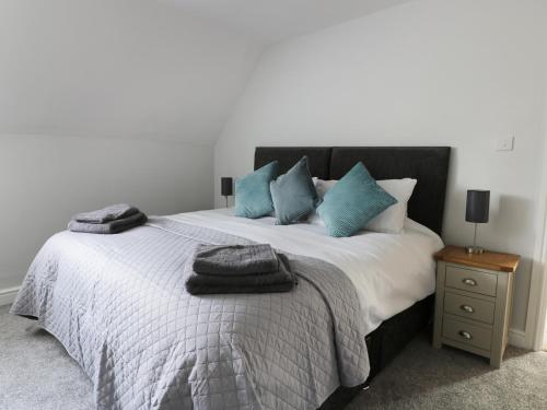 a bedroom with a bed with blue pillows on it at Corner View in Great Driffield