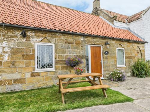 a wooden picnic table in front of a stone house at Milton Cottage in Whitby