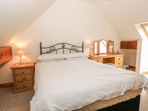 a bedroom with a large white bed and a mirror at Milton Cottage in Whitby