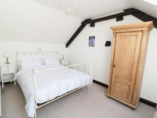 カークビームアサイドにあるThe Old Potting Shedの白いベッドと木製キャビネット付きのベッドルーム1室が備わります。