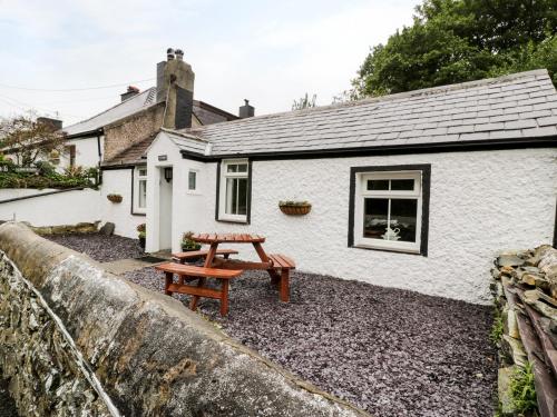 a white cottage with a picnic table in front of it at Ty Coed in Llanberis