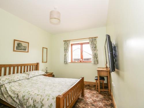 a bedroom with a bed and a tv and a window at The Cottage in Watchet