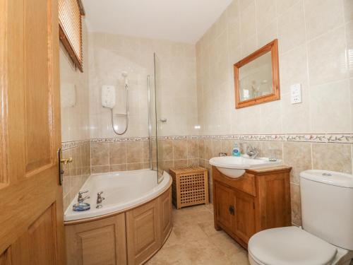 a bathroom with a tub and a toilet and a sink at The Cottage in Watchet