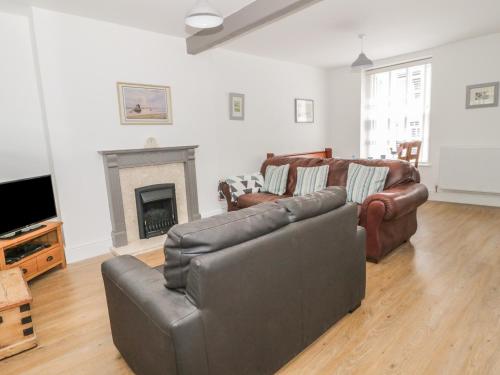 a living room with two leather couches and a fireplace at 22 Uppergate Street in Conwy