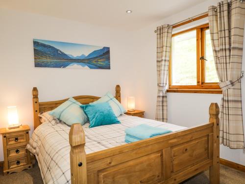a bedroom with a wooden bed and a window at The Ben in Leckmelm