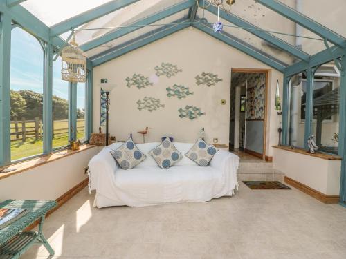 ein Wohnzimmer mit einer weißen Couch in einem Zimmer mit Fenstern in der Unterkunft Woolly Welcome in Penzance