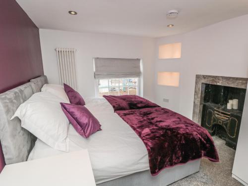 a bedroom with a large white bed with purple pillows at 11A Church Street in Whitby