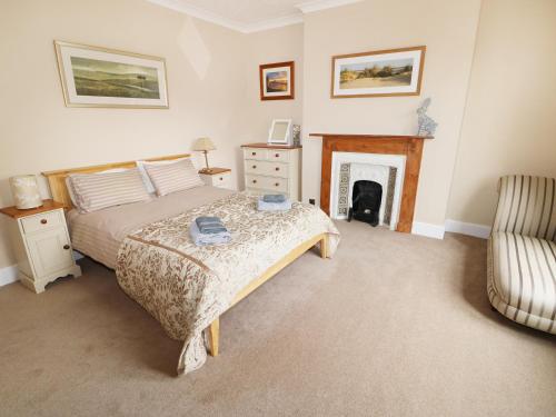 ein Schlafzimmer mit einem Bett und einem Stuhl und einem Kamin in der Unterkunft Tilly's Retreat in Hunstanton