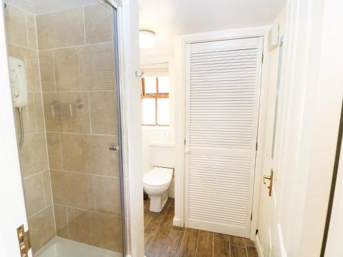 a bathroom with a toilet and a glass shower stall at The Granary in Lydney
