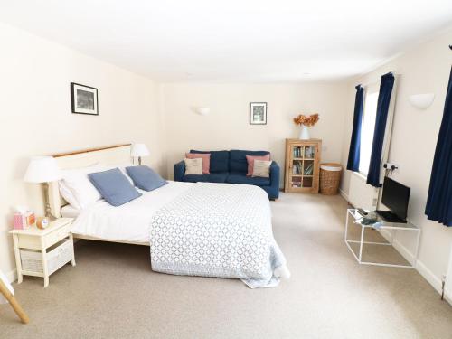 ein Schlafzimmer mit einem Bett und einem blauen Sofa in der Unterkunft The Granary in Lydney