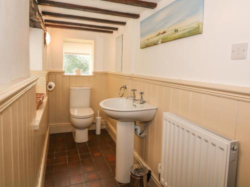 uma casa de banho com um lavatório branco e um WC. em Barn Cottage em Buxton