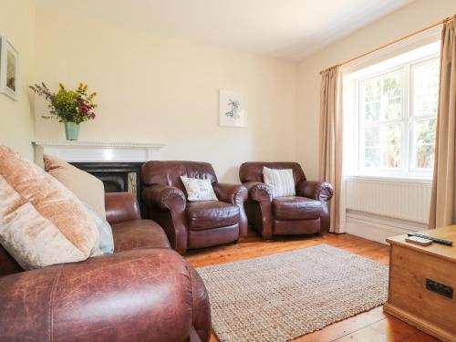 a living room with leather chairs and a fireplace at School House in Builth Wells