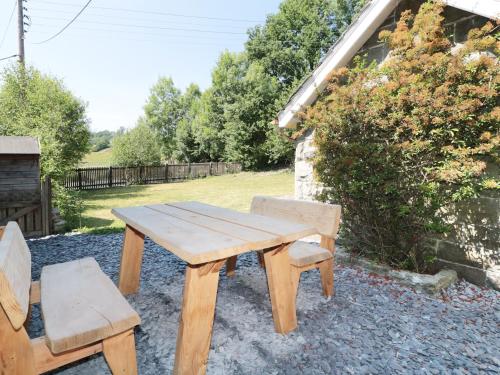 a wooden picnic table and two chairs in a yard at School House in Builth Wells
