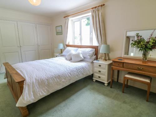 a bedroom with a bed and a dresser and a mirror at Wood View Cottage in Blackawton