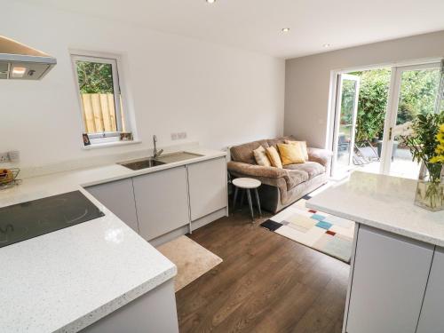 a kitchen with white counters and a couch in a room at Little Pippin in Carlyon Bay