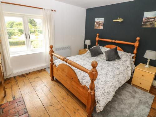 a bedroom with a wooden bed and a window at Callow Cottages in Ashbourne