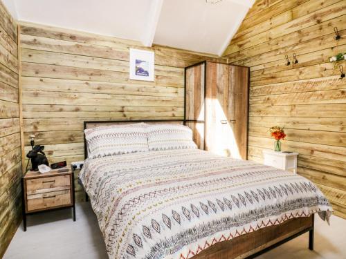 Un dormitorio con una pared de madera y una cama en Barn Acre Cottage en Newquay