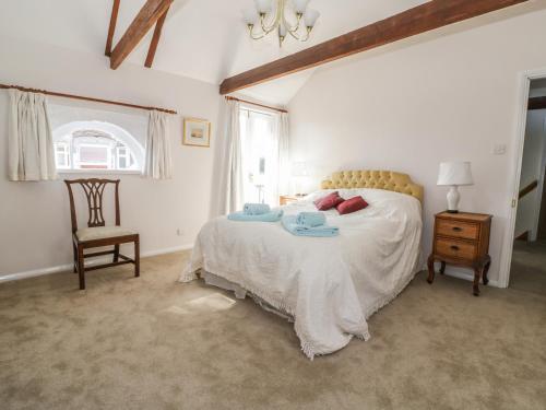 a bedroom with a bed and a chair and a window at Stable Cottage in Sudbury