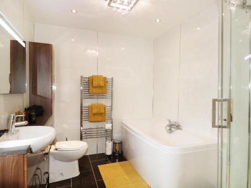 a bathroom with a tub and a toilet and a sink at Maclean Cottage in Beauly