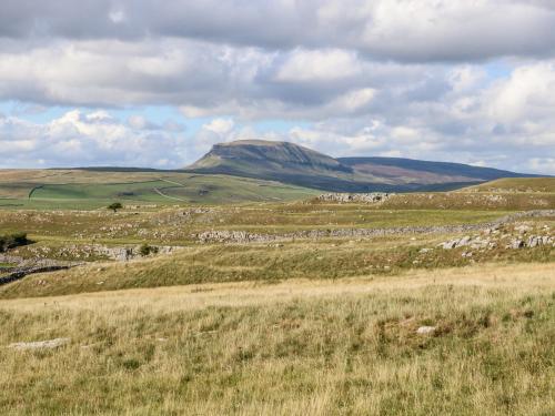 a field of grass with a mountain in the background at Melsome Barn in Settle