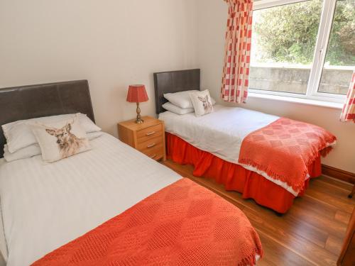 two beds in a room with a window at Broadford Farm Bungalow in Kidwelly