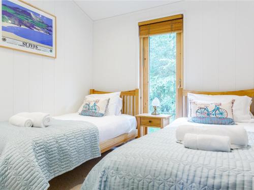 a bedroom with two beds and a window at 8 Streamside in Looe