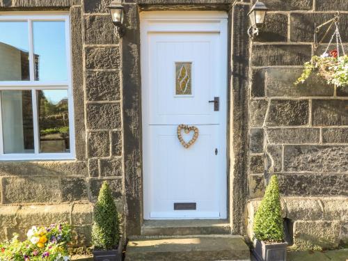 a white door on a stone house with a wreath on it at The Cottage, Beeston Hall in Sowerby Bridge