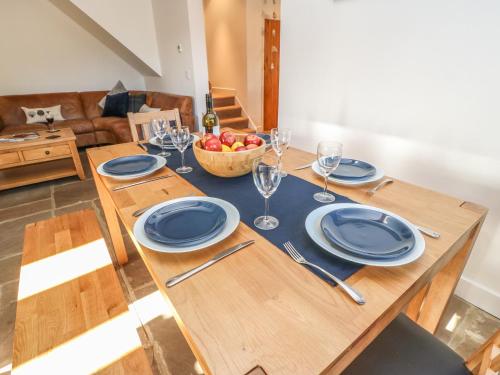 a wooden table with plates and glasses and a bowl of fruit at The Cottage, Beeston Hall in Sowerby Bridge