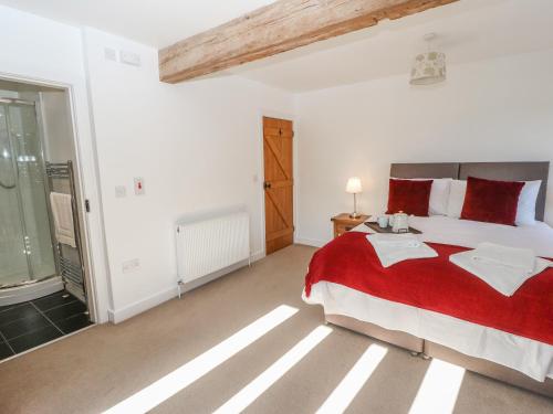 a bedroom with a large bed with a red blanket at The Cottage, Beeston Hall in Sowerby Bridge