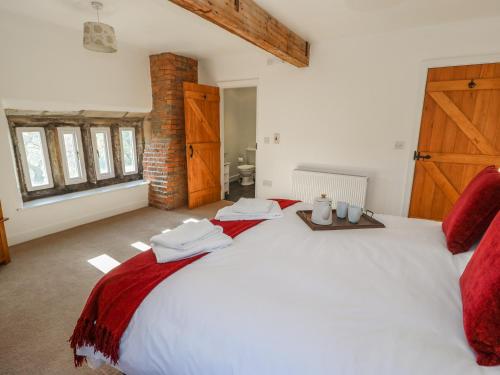 a bedroom with a large white bed with red sheets at The Cottage, Beeston Hall in Sowerby Bridge