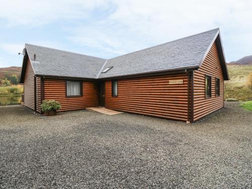 a large wooden cabin with a gravel driveway at Burnside Lodge Lodge 1, Glengoulandie in Aberfeldy