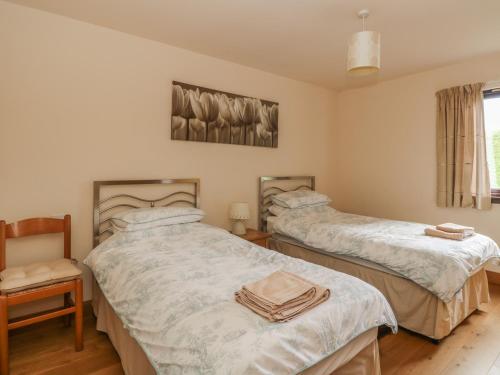 a bedroom with two beds and a chair and a window at Burnside Lodge Lodge 1, Glengoulandie in Aberfeldy