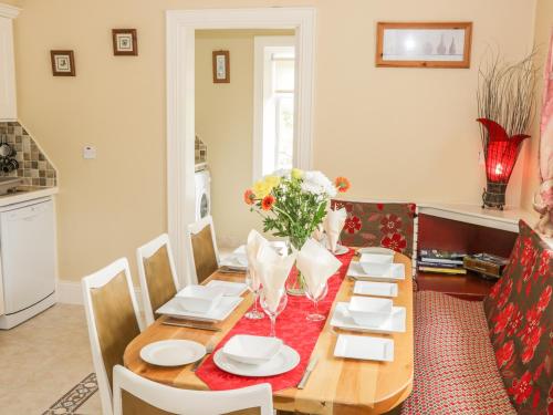 a dining room with a wooden table with chairs and flowers at Cnoc suan in Carrigallen