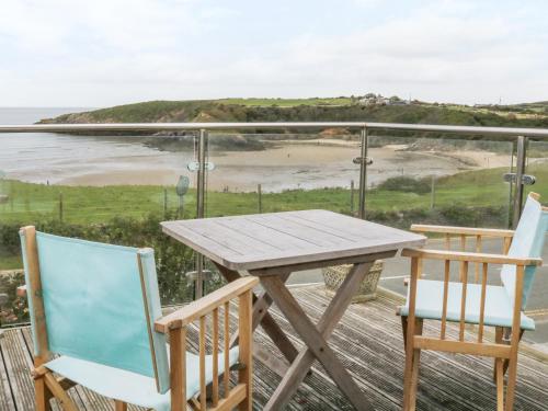 a table and chairs on a balcony with a view of a beach at Cable House in Cemaes Bay