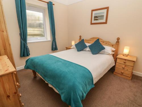 ein Schlafzimmer mit einem Bett mit blauen Vorhängen und einem Fenster in der Unterkunft Treleigh in Hayle