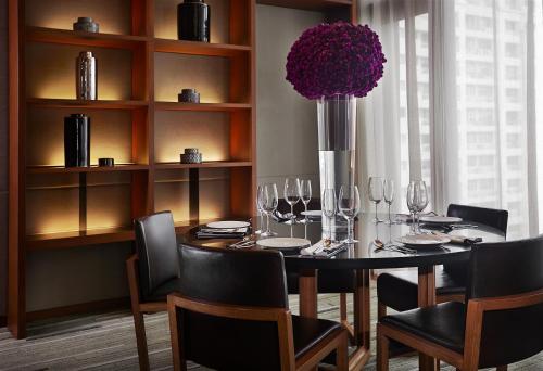 a dining room with a table with chairs and a vase with flowers at Hansar Bangkok - SHA Extra Plus in Bangkok